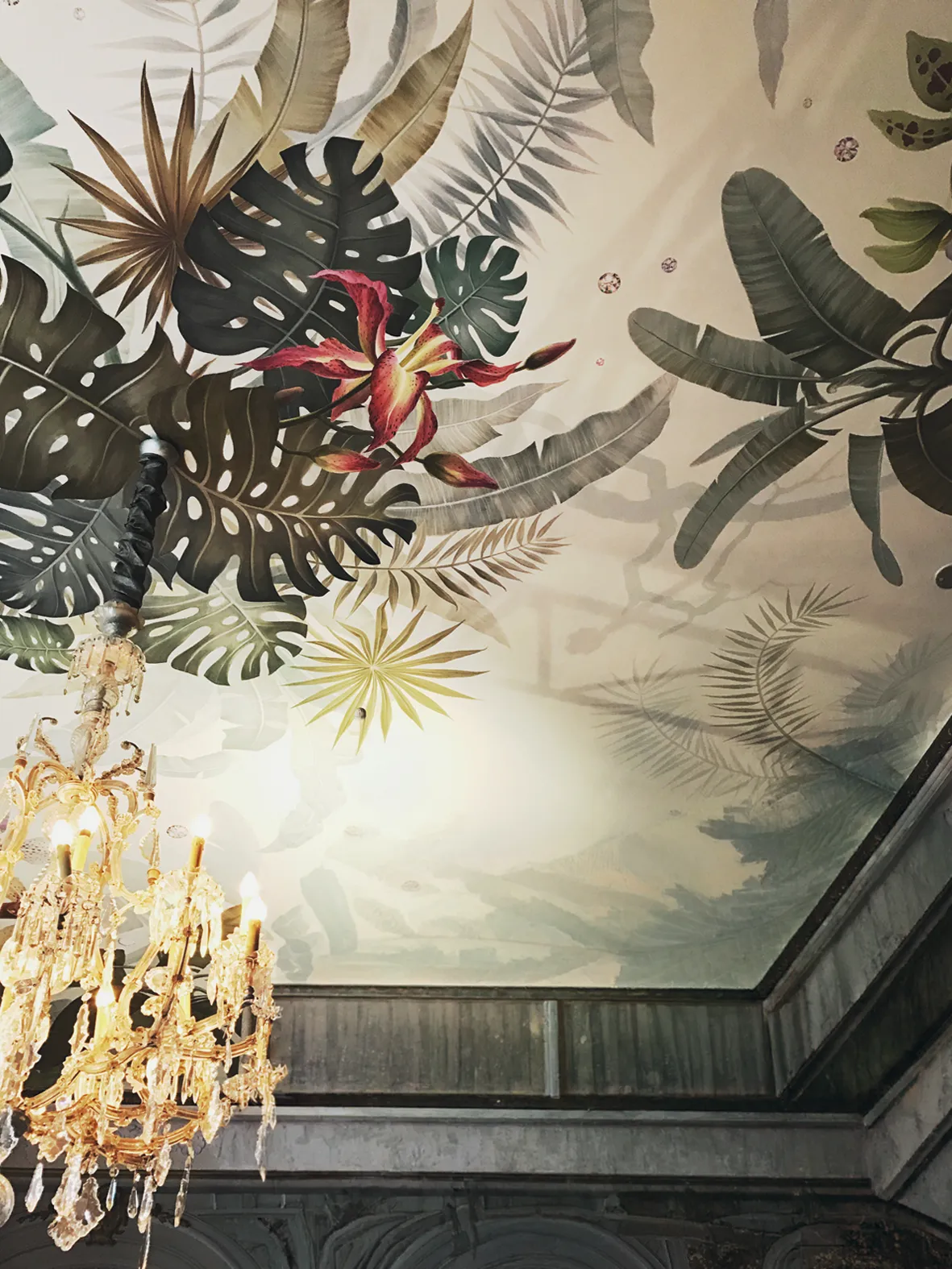 Deckenmalerei mit tropischen Palm- und Monstera-Blättern, roter Lilienblüte und vergoldetem Kristall-Kronleuchter