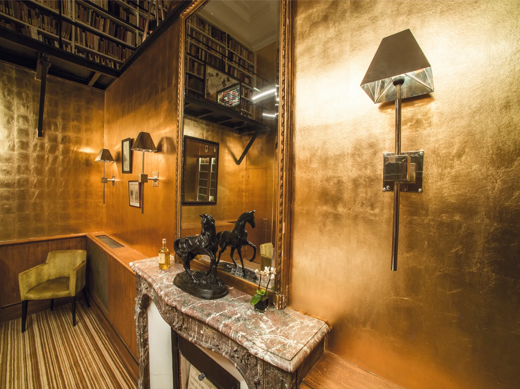 Hotelsalon mit gold-metallischer Karat-Wandfläche, antiker Marmorkonsole mit Bronze-Pferdeskulpturen und vergoldetem Wandspiegel