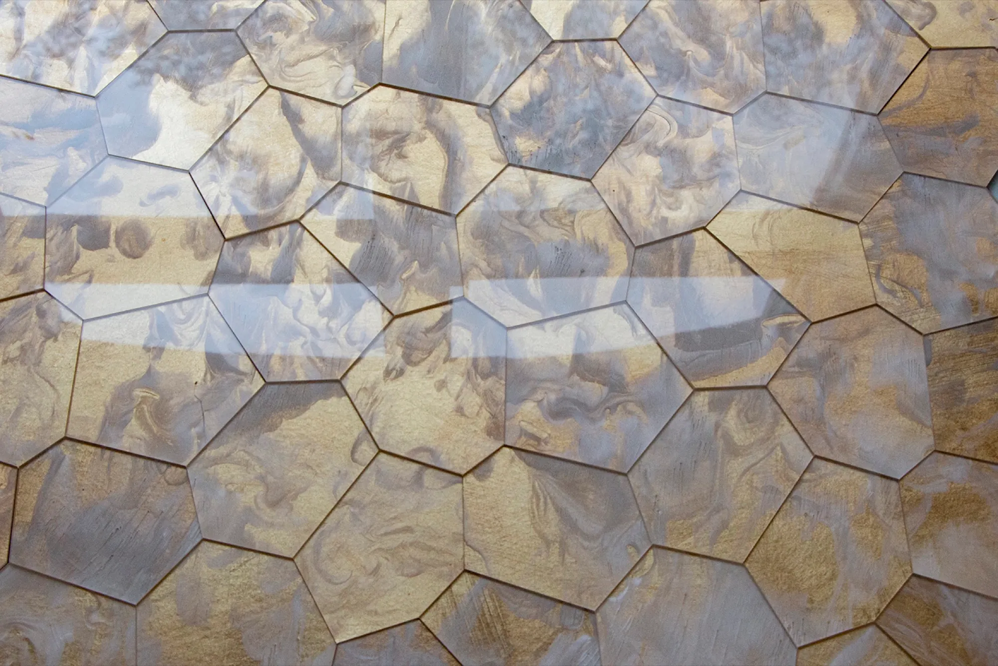 Detail einer Polygon-Glasfläche in Gold und Blaugrau