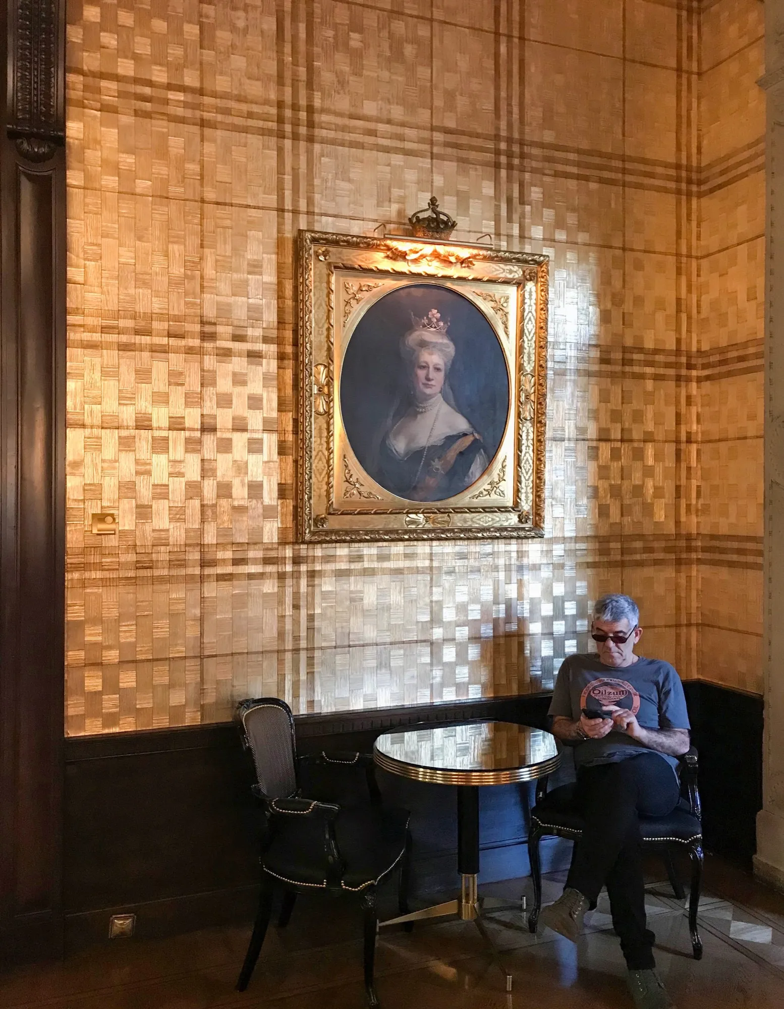 Salón de hotel con superficie Karat dorada, retrato enmarcado de dama con corona y conjunto clásico de asientos