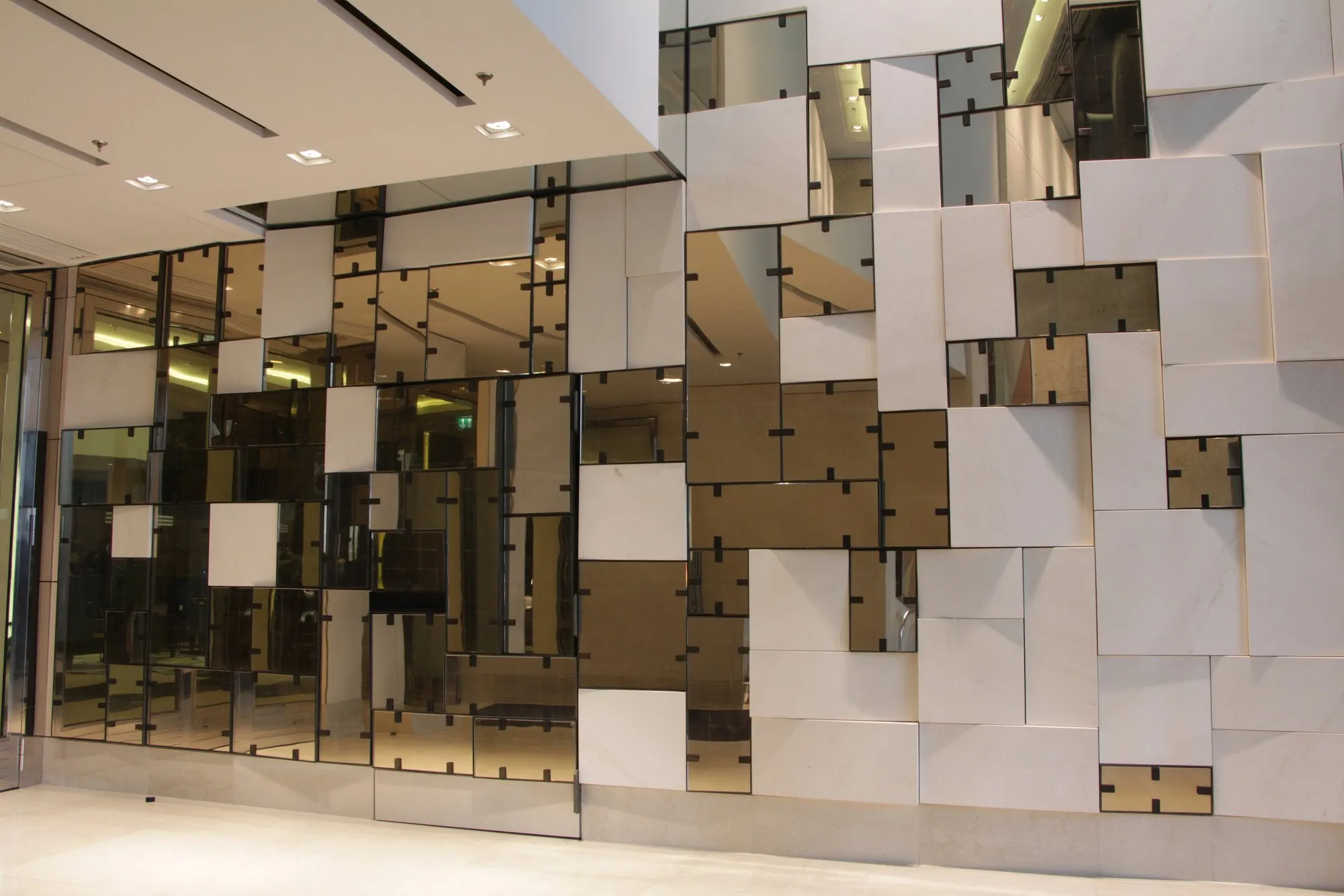 Foyerwand aus versetzten Glas-, Spiegel- und Steinplatten in Bronze-, Silber- und Cremetönen, Waldorf Astoria