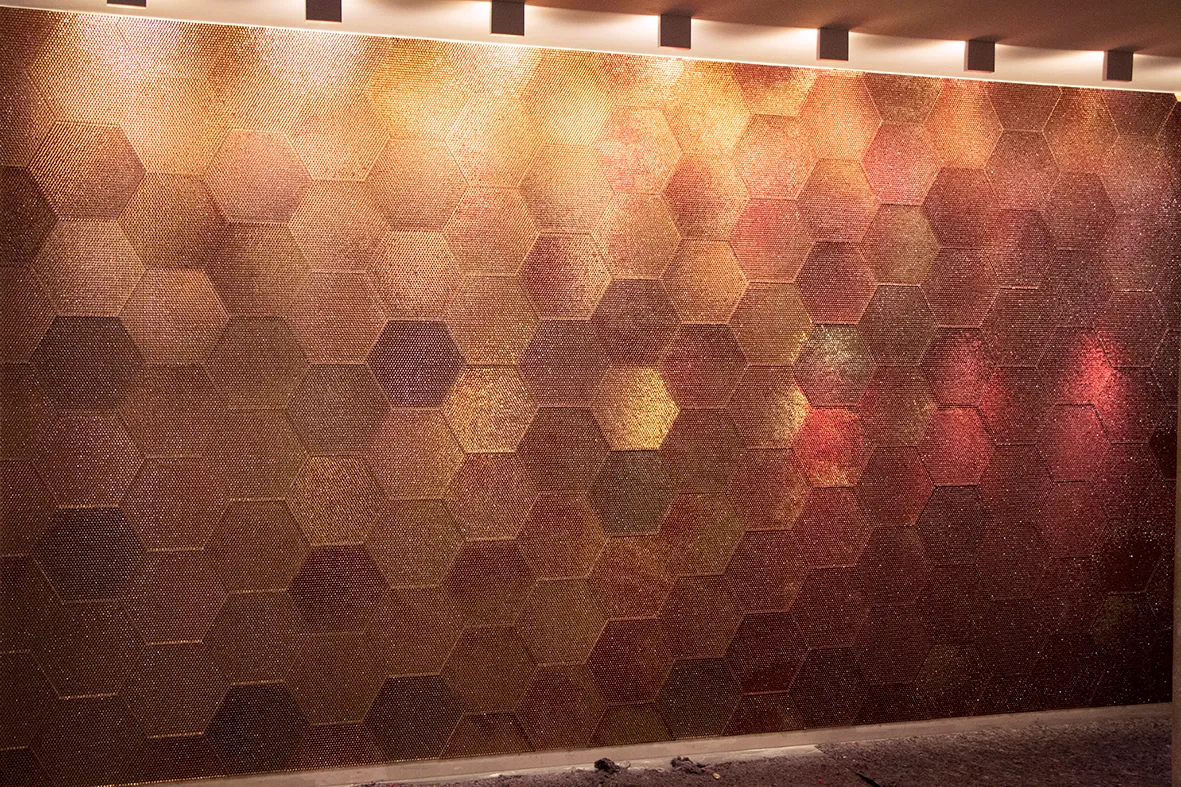 Wandfläche aus großen Hexagon-Paneelen in Kupfer-, Burgunder- und Goldtönen