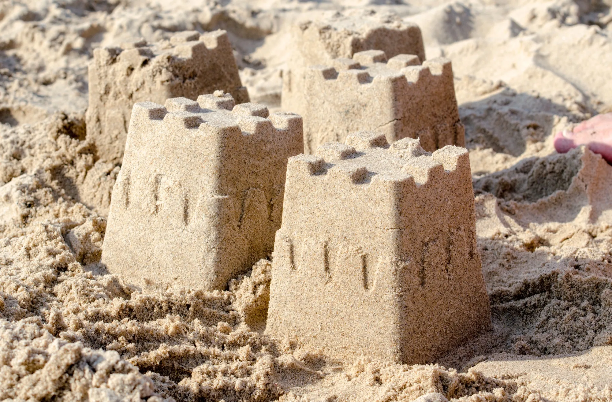 Varios pequeños castillos de arena con almenas en la playa