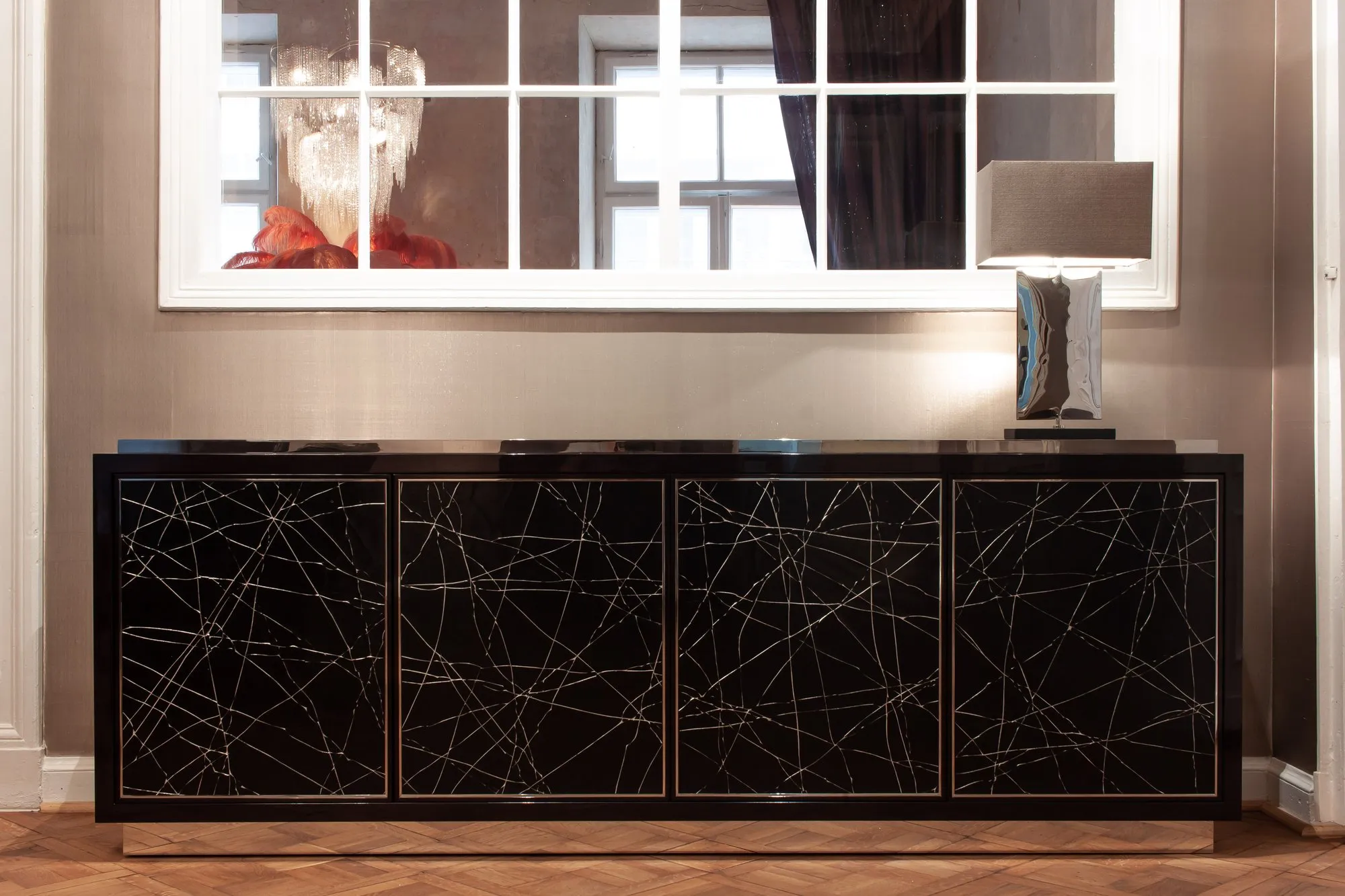 Niedriges Sideboard mit hochglänzend schwarzer Oberfläche und feinen weißen Bruchlinien